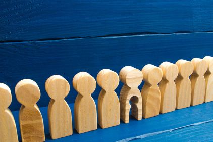 Foto: Holzfiguren in einer Reihe, eine hat ein ausgeschnittenes Kind